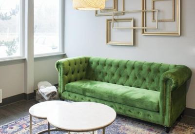 Lounge area with a vibrant green velvet sofa and circular white coffee tables.