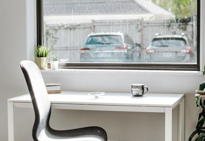 Bright workspace featuring a white desk and ergonomic chair by a large window.