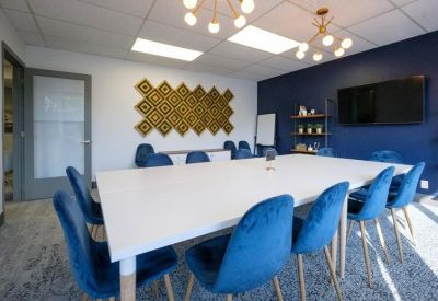 Meeting room with a large white table, blue velvet chairs, and a navy feature wall.
