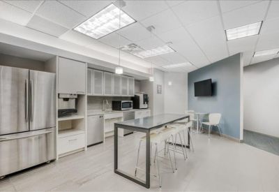 Modern breakroom kitchen with stainless steel appliances and a long high-top table.