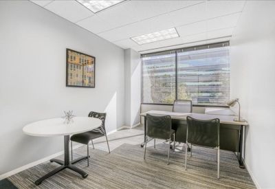 Private office with a round meeting table, desk, and large window.