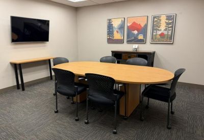 Meeting room with an oval table, black chairs, and three framed nature prints on the wall.