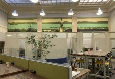 Open workspace featuring high-top wooden tables and a large scenic mural on the wall.