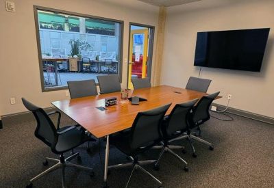 Professional meeting room with a large wooden conference table and wall-mounted screen.