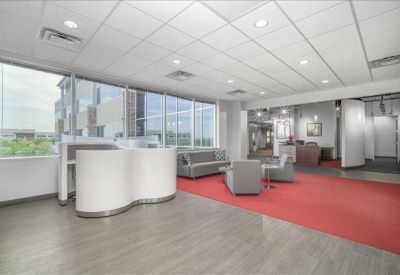 Bright lobby area with a curved white reception desk and red carpeting.