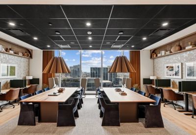 Long wooden coworking tables under unique pendant lights with city views.