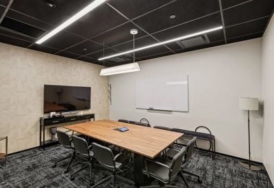 Meeting room with a wooden table, white board, and wall-mounted TV.