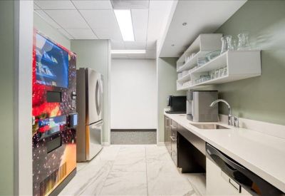 Modern kitchen and break area with white countertops and a high-tech vending machine.