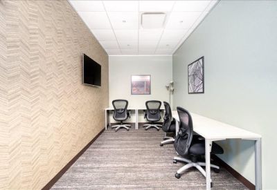 Narrow private office with a patterned feature wall and ergonomic chairs.