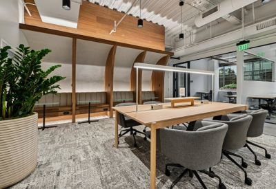 Modern coworking area with curved wood partitions and soft bench seating.