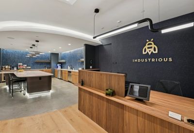 Modern reception area with a wood-slat desk and Industrious branding on a dark wall.