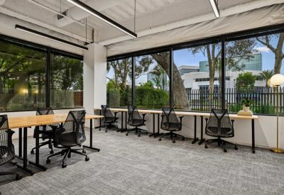 Bright office suite featuring several workstations along a large window wall.