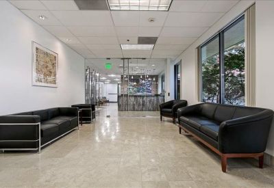 Bright lobby area with black leather sofas and polished stone flooring.