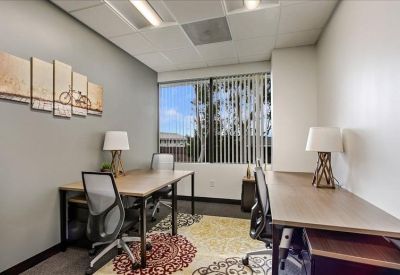Private office suite with two workstations, large window, and patterned area rug.