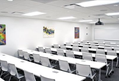 Large seminar room with rows of white desks and bright modern lighting.