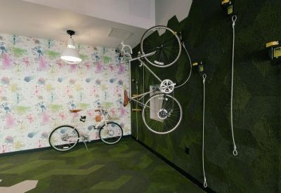 Playful communal space featuring a bicycle wall mount, patterned wallpaper, and green geometric carpet.
