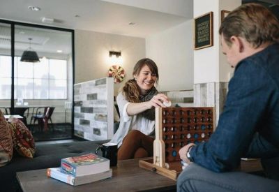 Coworking lounge where people are playing a wooden tabletop game on a dark sofa.