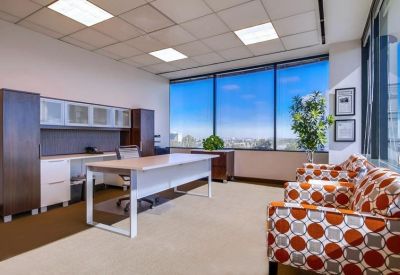 Spacious private office with a large desk and vibrant orange patterned armchairs.