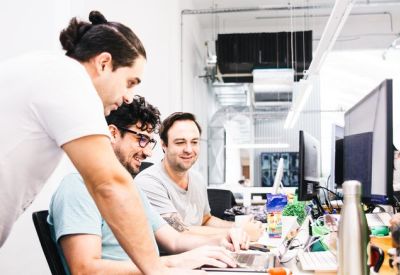 Colleagues collaborating at a long white desk in a bright, modern open-plan office setting.
