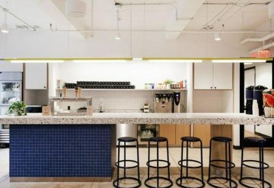 Modern office kitchen with a blue tiled island and high bar stools.