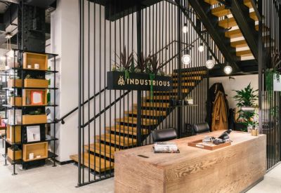 Reception desk featuring warm wood textures, industrial stairs, and branded signage.