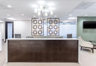 Professional reception area with a dark wood desk, decorative screens, and a waiting lounge.
