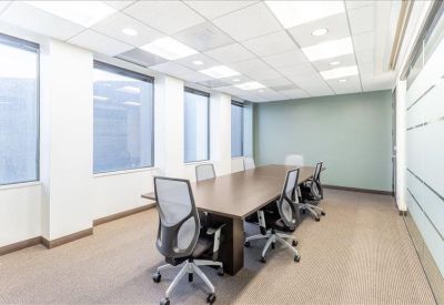 Spacious boardroom with a large wooden table, several mesh chairs, and large windows.