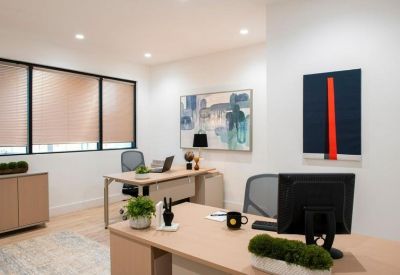 Private office with two desks, modern chairs, and abstract art on the walls.