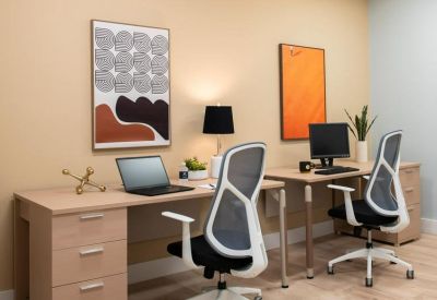 Shared two-person office suite featuring light wood desks and abstract wall art.