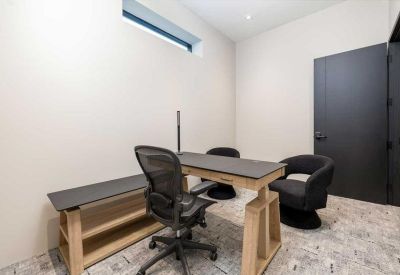 Bright private office featuring a modern wooden desk, ergonomic chair, and high window.