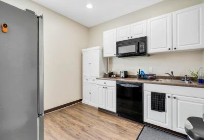 Modern kitchen area with white cabinetry, black microwave, and dishwasher.