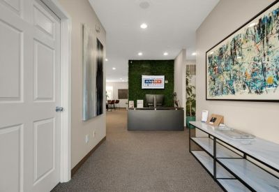 Reception area with a grey front desk and green moss feature wall.