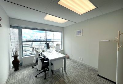 Private office featuring a white desk, two ergonomic chairs, and a large window with harbor views.