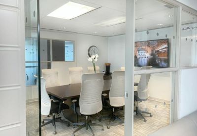 Meeting room with a long dark wood table, white mesh chairs, and a glass-enclosed wall.