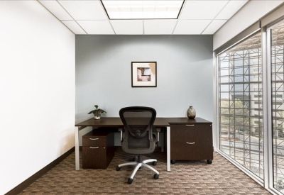 Private office with a dark wood desk and large window view.