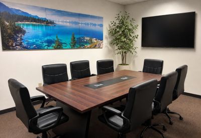 Professional conference room with a large wooden table, black leather chairs, and a lake mural.