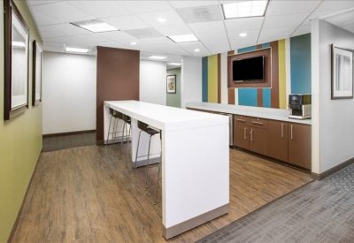 Modern communal breakroom with a high white breakfast bar and colourful striped feature wall.