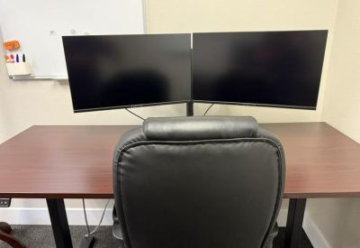 Private office workstation with dual monitors, ergonomic chair, and whiteboard.