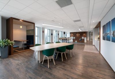 Modern communal area featuring a wood-panelled booth, dining table, and dark green chairs.