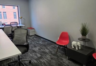 Private office featuring white desks, grey ergonomic chairs, and vibrant red accent seating.