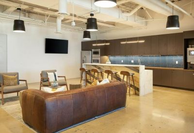 Modern breakroom lounge featuring a large leather sofa and a marble-top bar area with stools.