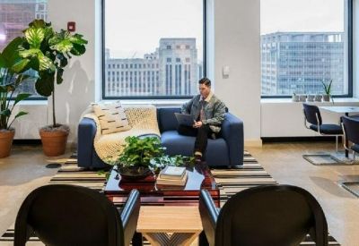Bright lounge area with a blue sofa, large windows, and city skyline views.