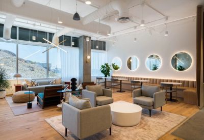 Spacious communal lounge with grey armchairs, circular mirrors, and a tan banquet seat.