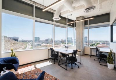 Bright office space with six ergonomic workstations and expansive city views through large windows.