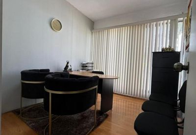 Bright private office featuring black velvet armchairs, a rug, and vertical window blinds.