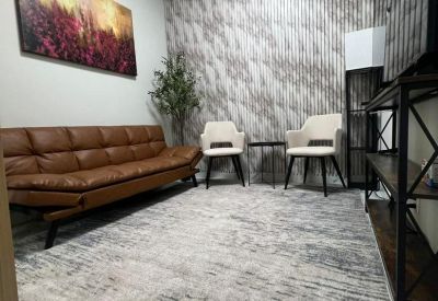Lounge area featuring a brown leather sofa, patterned rug, and wall art.