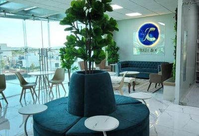 Curved teal velvet bench seating around a central indoor tree in a bright lobby.