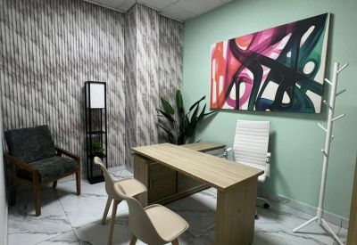 Private office with light wood desk, white leather chair, and abstract art.