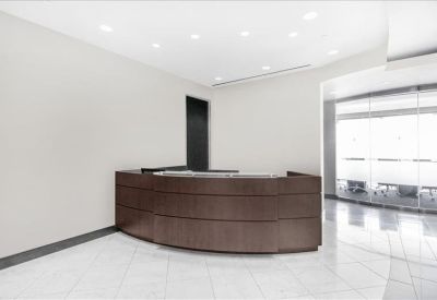 Modern reception area with a dark curved wood desk and bright white floors.