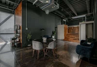 Industrial style breakout space with dark walls and large windows.